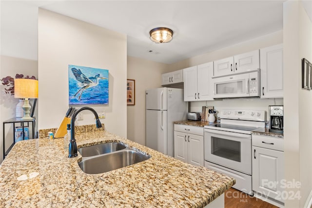 kitchen featuring white cabinetry, light stone countertops, white appliances, and sink