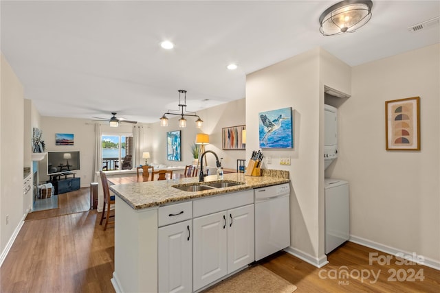 kitchen with dishwasher, white cabinetry, kitchen peninsula, and stacked washer and clothes dryer