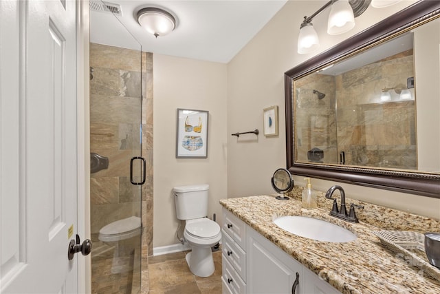 bathroom featuring vanity, a shower with shower door, and toilet