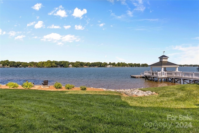 view of dock with a gazebo, a water view, and a lawn