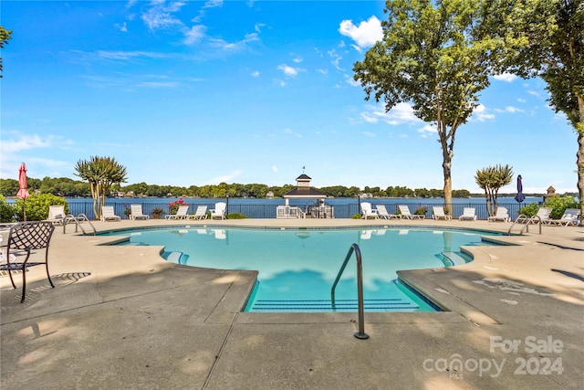 view of swimming pool with a water view and a patio