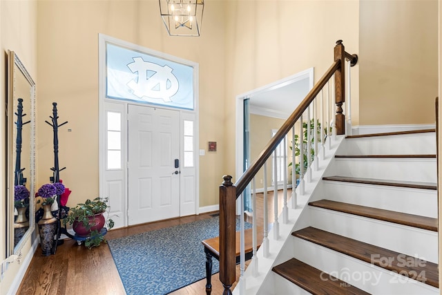 foyer featuring a chandelier, a towering ceiling, hardwood / wood-style flooring, and crown molding