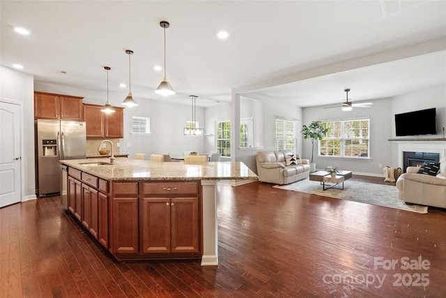 kitchen with open floor plan, stainless steel refrigerator with ice dispenser, dark wood-style flooring, and a sink