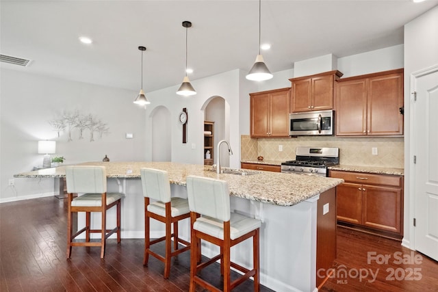 kitchen featuring brown cabinets, visible vents, appliances with stainless steel finishes, and a sink