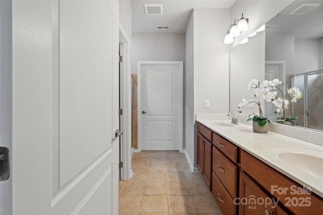 full bath with double vanity, a stall shower, visible vents, and a sink