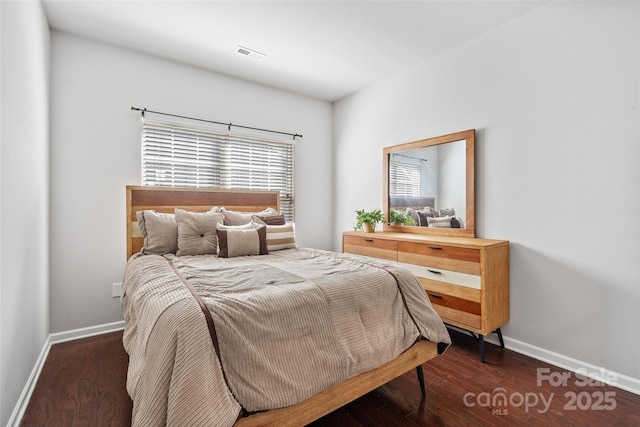 bedroom featuring visible vents, baseboards, and wood finished floors