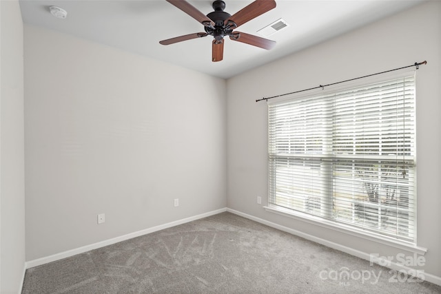 carpeted empty room featuring baseboards, visible vents, and ceiling fan