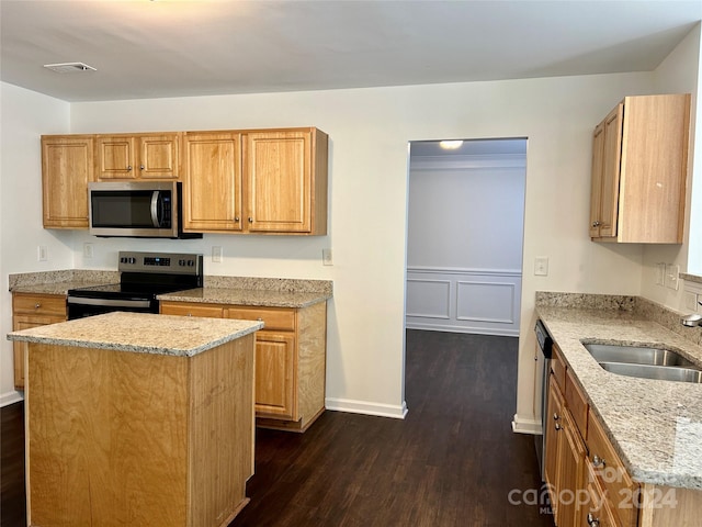 kitchen with light stone countertops, appliances with stainless steel finishes, dark hardwood / wood-style flooring, sink, and a kitchen island