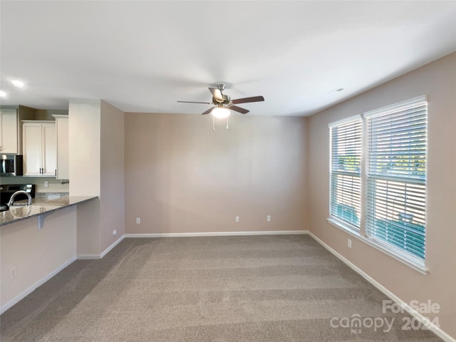 spare room featuring light colored carpet and ceiling fan