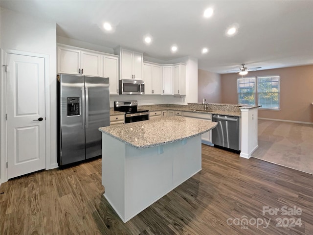 kitchen featuring dark hardwood / wood-style floors, kitchen peninsula, a center island, white cabinets, and appliances with stainless steel finishes