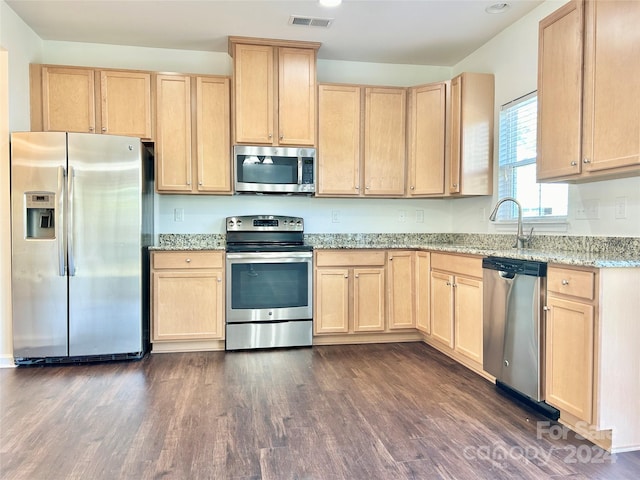 kitchen featuring dark wood-type flooring, light stone countertops, light brown cabinets, and stainless steel appliances