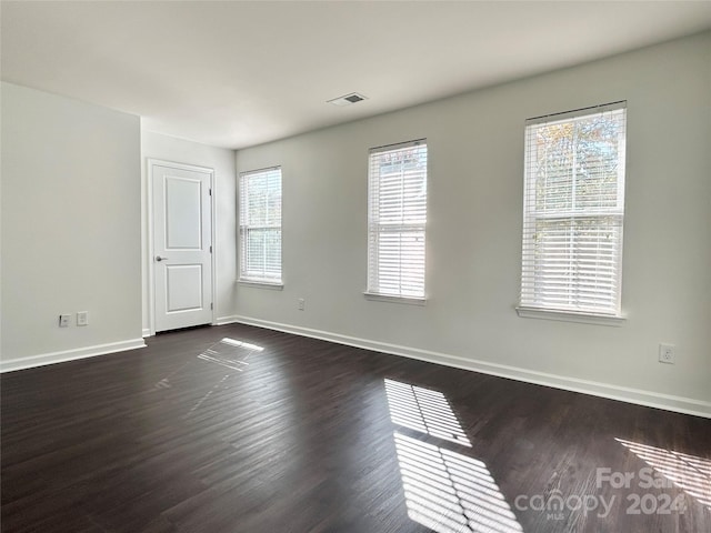 empty room with plenty of natural light and dark hardwood / wood-style floors