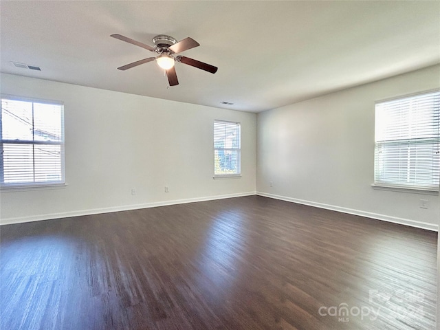 empty room featuring dark hardwood / wood-style floors, ceiling fan, and a wealth of natural light