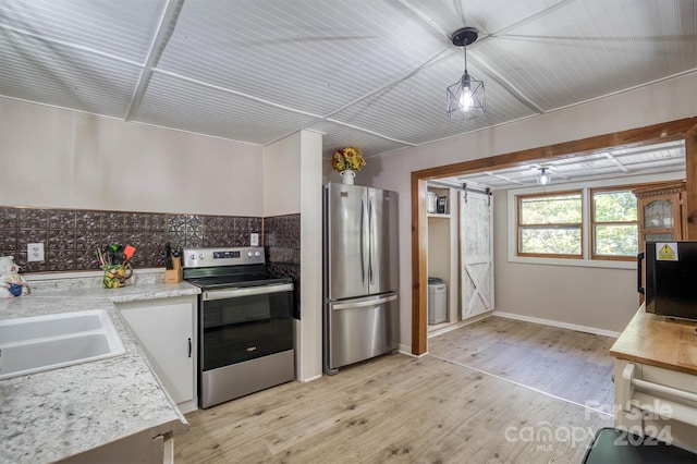 kitchen featuring white cabinetry, decorative light fixtures, stainless steel appliances, and light wood-type flooring