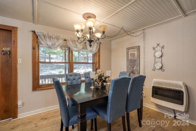 dining room with wood walls, a chandelier, heating unit, and hardwood / wood-style flooring