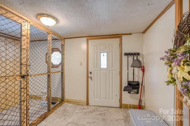 foyer entrance with ornamental molding and a textured ceiling