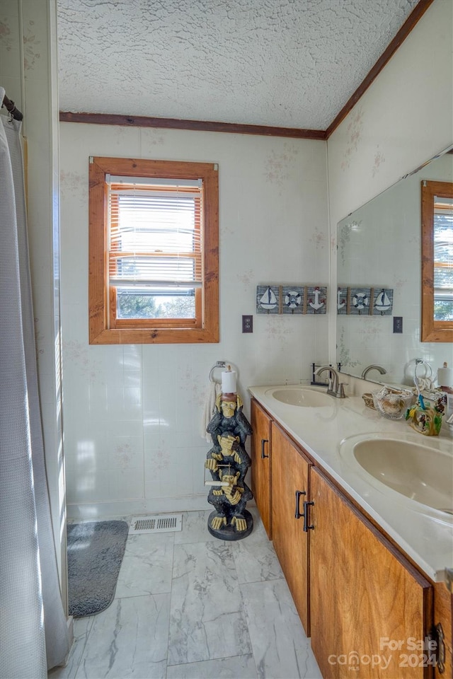 bathroom featuring vanity, ornamental molding, and a textured ceiling