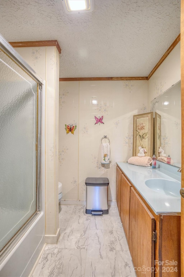 full bathroom featuring toilet, crown molding, bath / shower combo with glass door, vanity, and a textured ceiling