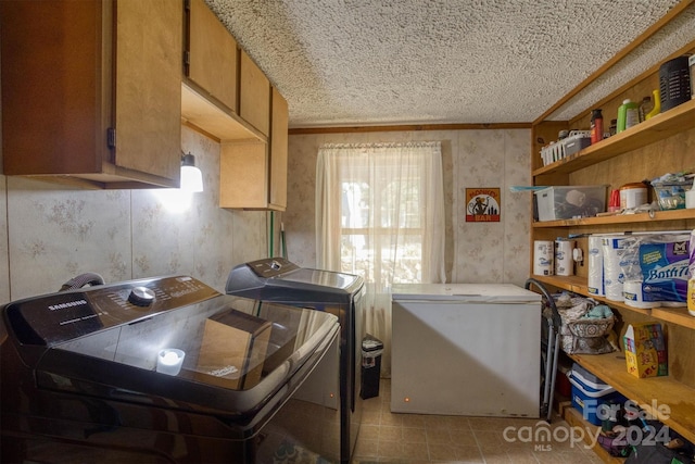 clothes washing area featuring a textured ceiling, washer and clothes dryer, cabinets, and ornamental molding