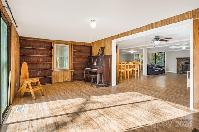 unfurnished room with wooden walls, wood-type flooring, and ceiling fan