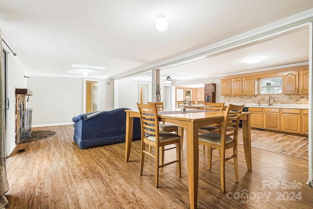 dining area featuring ornamental molding, sink, light wood-type flooring, and ceiling fan