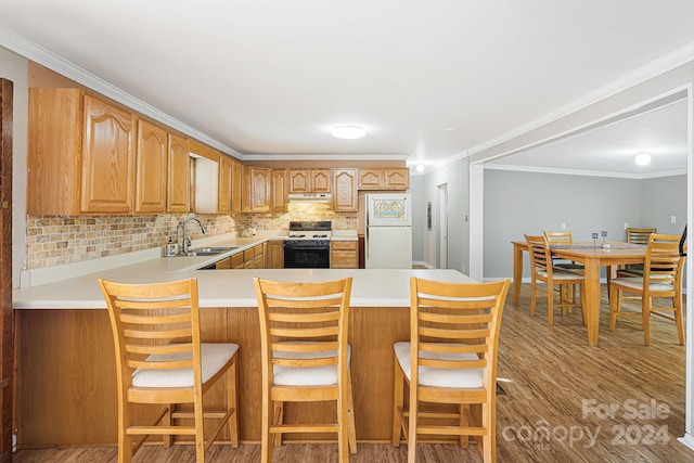 kitchen featuring a breakfast bar area, sink, light wood-type flooring, and white appliances