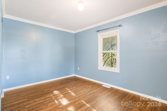 empty room featuring ornamental molding and wood-type flooring