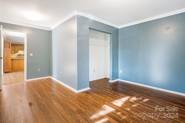 unfurnished bedroom with dark wood-type flooring, crown molding, and a closet