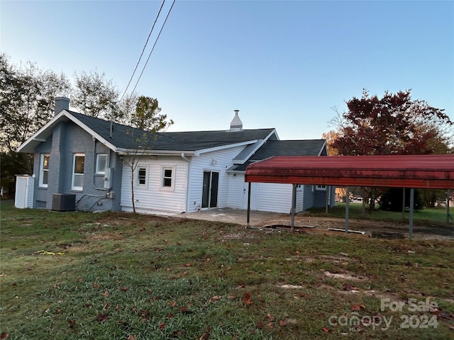 rear view of house featuring a patio area, central AC, a lawn, and a carport