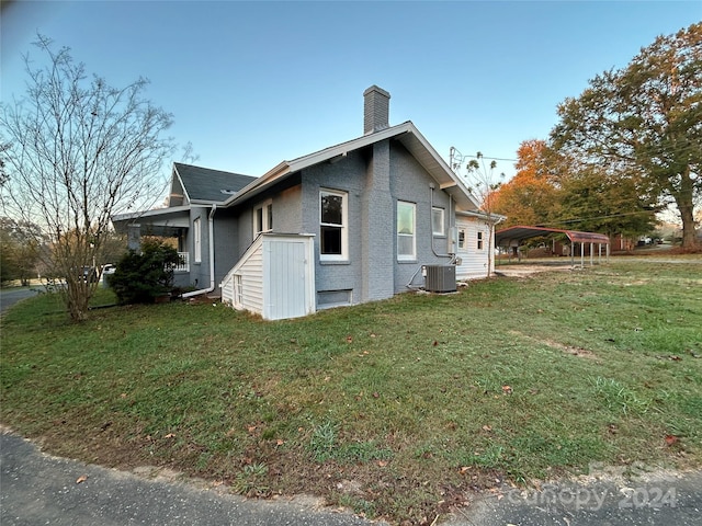 view of side of home featuring central AC and a yard