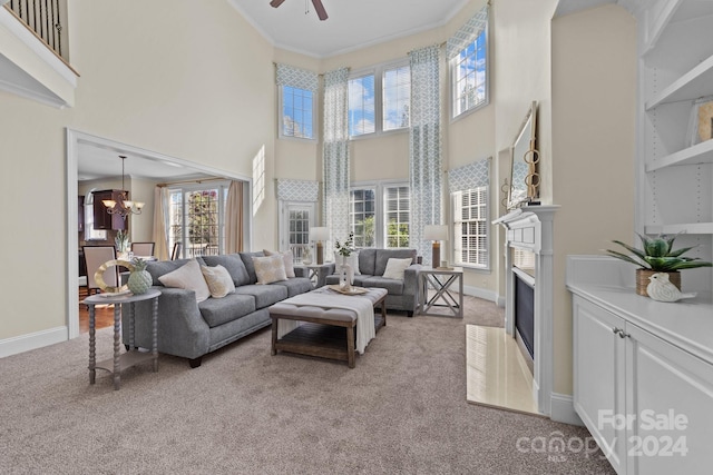 living room featuring light carpet, crown molding, a high ceiling, and ceiling fan with notable chandelier