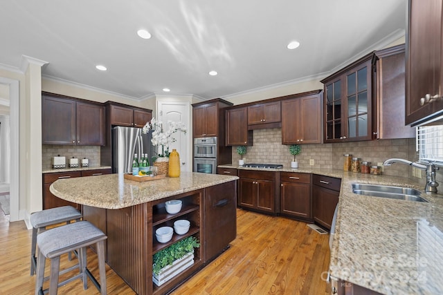 kitchen with light stone countertops, ornamental molding, sink, light hardwood / wood-style floors, and stainless steel appliances