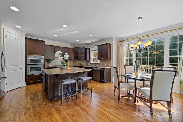 kitchen with dark brown cabinetry, stainless steel appliances, light wood-type flooring, and a kitchen island