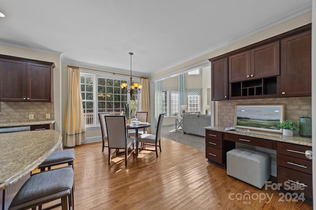 kitchen with light hardwood / wood-style flooring, light stone countertops, decorative light fixtures, and dark brown cabinets