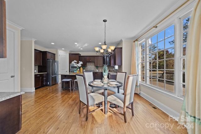 dining space featuring ornamental molding, a notable chandelier, and light wood-type flooring