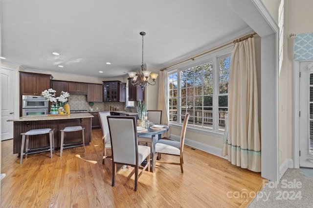 dining room featuring an inviting chandelier, crown molding, and light wood-type flooring