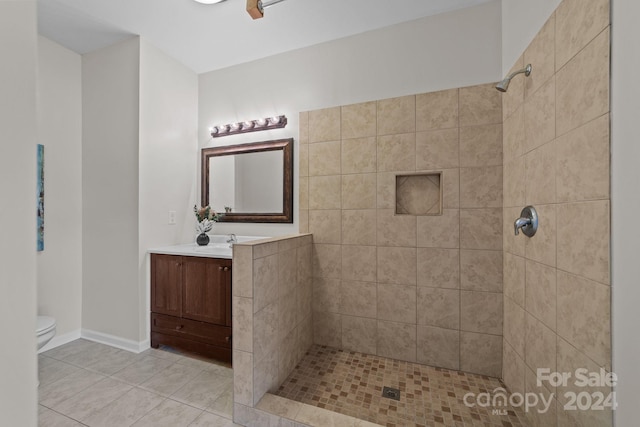 bathroom featuring vanity, a tile shower, toilet, and tile patterned flooring