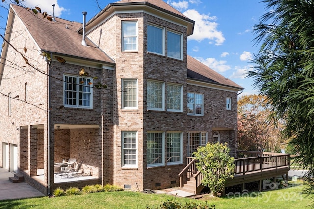 back of property with a patio area, a deck, a lawn, and a garage