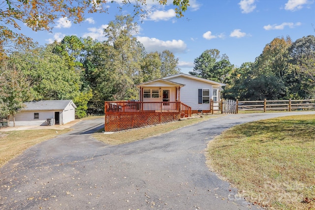 view of front of property featuring an outdoor structure, a deck, and a front lawn