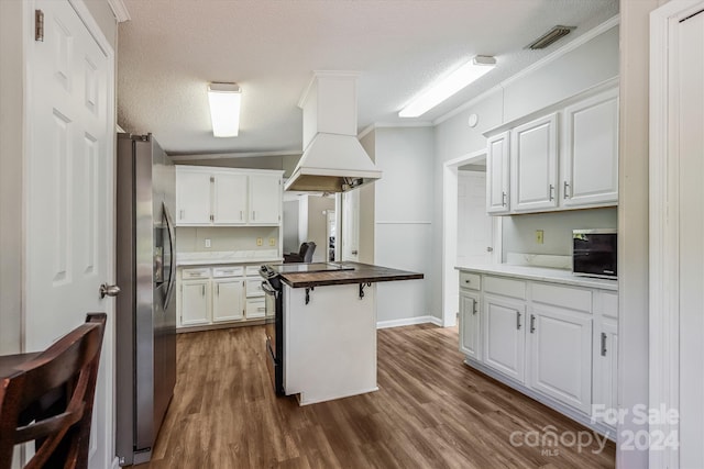 kitchen featuring wood counters, premium range hood, stainless steel refrigerator with ice dispenser, and white cabinets