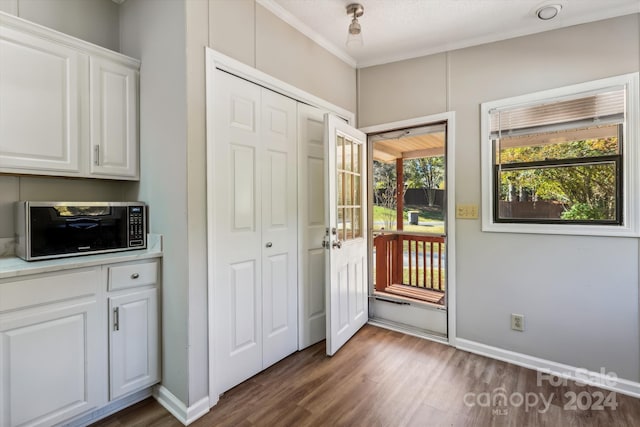 doorway featuring crown molding, a textured ceiling, and dark hardwood / wood-style flooring