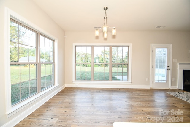 unfurnished dining area featuring a chandelier and wood-type flooring