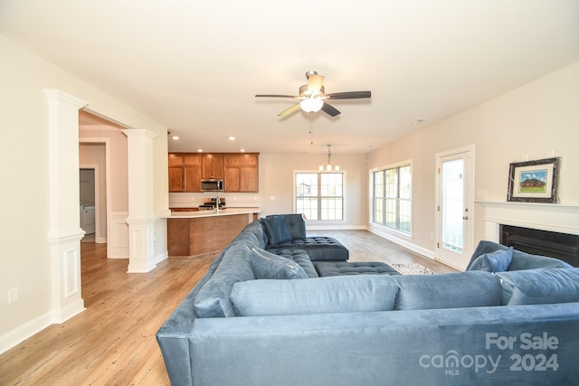 living room with ornate columns, ceiling fan, and light hardwood / wood-style flooring