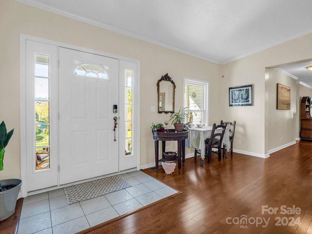 entryway with ornamental molding and hardwood / wood-style floors