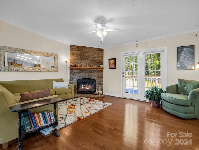 living room featuring a stone fireplace, hardwood / wood-style floors, ceiling fan, and ornamental molding