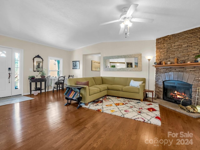 living room featuring a stone fireplace, a textured ceiling, wood-type flooring, and ceiling fan