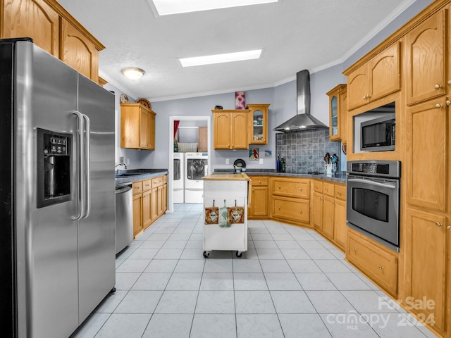 kitchen featuring washer and dryer, stainless steel appliances, wall chimney exhaust hood, vaulted ceiling, and crown molding