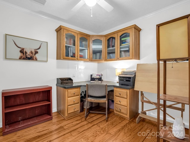 office featuring built in desk, a textured ceiling, ornamental molding, and light hardwood / wood-style flooring