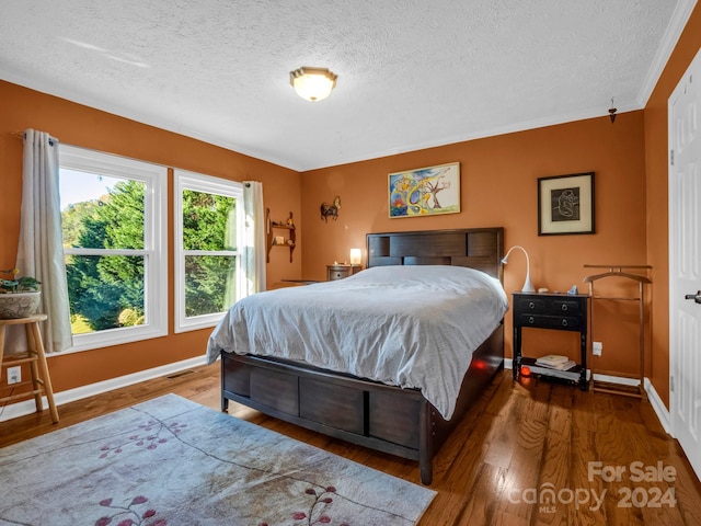 bedroom featuring ornamental molding, hardwood / wood-style floors, and a textured ceiling