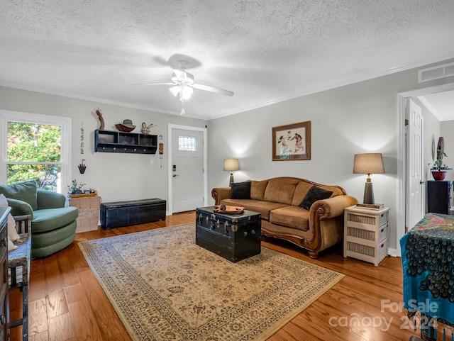 living room featuring ornamental molding, hardwood / wood-style floors, a textured ceiling, and ceiling fan